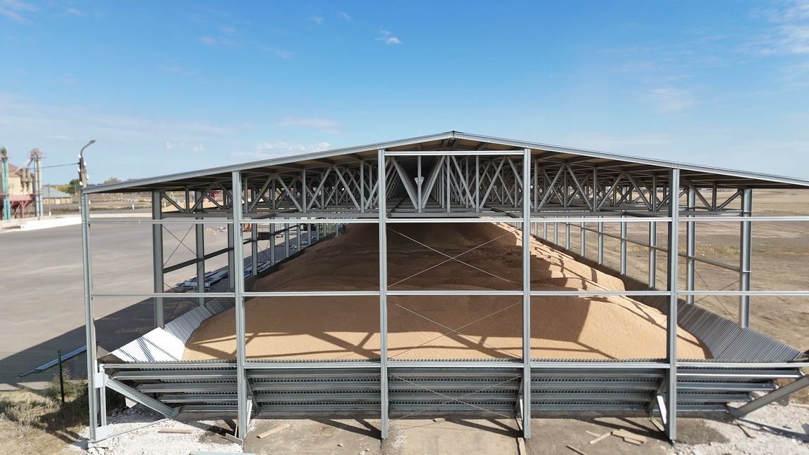Готовое напольное зернохранилище на каркасе завода Steppe Steel: фермы, наклонные стены, зерно под кровлей, вид с дрона